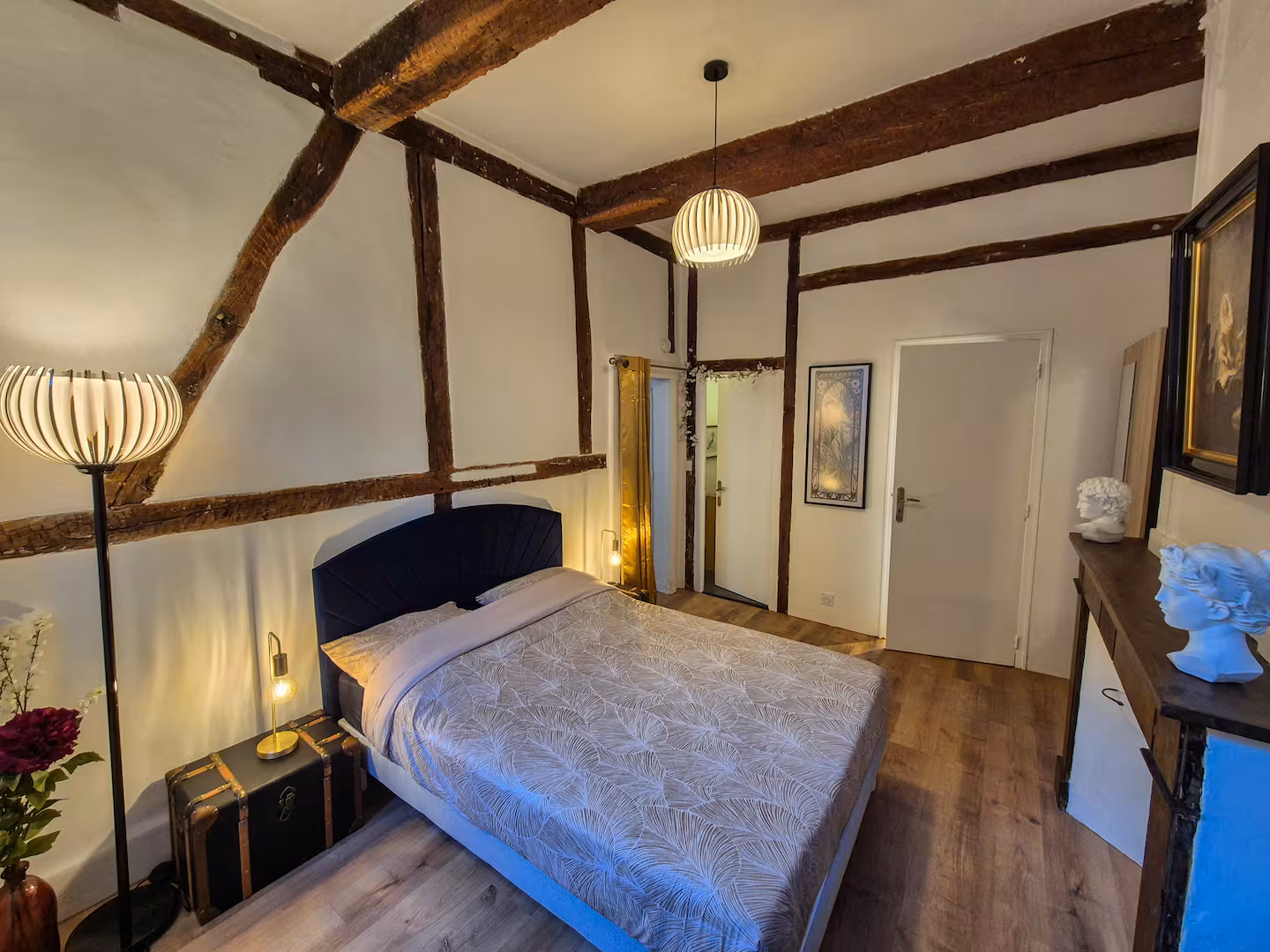 Une chambre à Albi : lit fait, poutres apparentes, lampes allumées